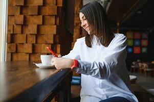 retrato de una hermosa niña con su teléfono móvil en la cafetería. foto