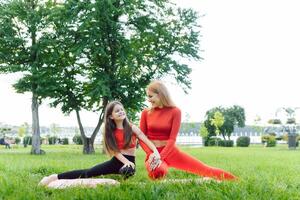 woman and child do yoga in the park. summer, sun, mother and daughter, health. outdoor sports. healthy sport lifestyle. fitness, yoga photo