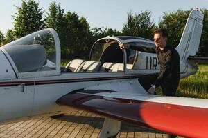 Pensive attrative young man pilot standing near small aircraft photo