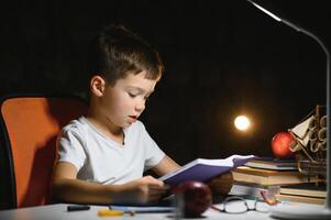 Boy learn lessons in the home setting at the table in the light of a table lamp. photo