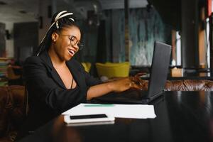 joven africano americano mujer emplazamiento a café trabajando en ordenador portátil foto