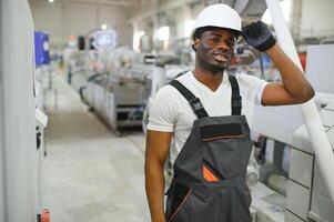Portrait of African American male engineer in uniform and standing in industrial factory photo