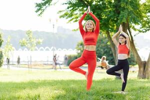 madre y hija haciendo yoga ejercicios en césped en el parque a el día hora foto