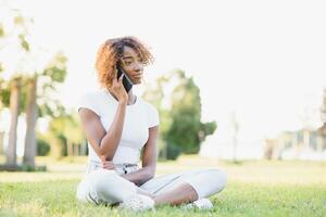 people, technology and leisure concept - happy african american young woman calling on smartphone outdoors photo