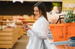 joven mujer leyendo información acerca de el producto en el teléfono foto