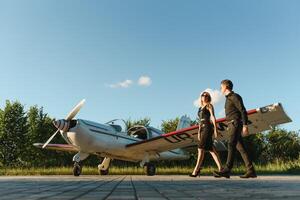 Portrait of two smiling business people, man and woman, walking by plane hangar in airport field photo