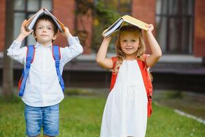 Happy children go back to school. Pupil of primary school go study with backpack outdoors. Kids go hand in hand. Beginning of lessons. First day of fall. Boy and girl from elementary student. photo