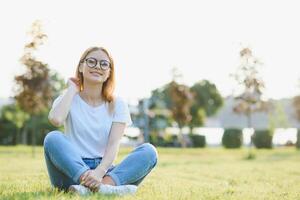 Portrait of a beautiful young woman or girl on very green meadow watching the sunset enjoying nature summer evening outdoors. Sunshine. Copy space. photo