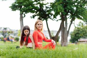 Mother practicing yoga with her daughter in the open air. photo