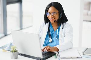 Portrait of african american happy smiling young doctor in headset consulting patient over the phone. Health care call center online concept. photo