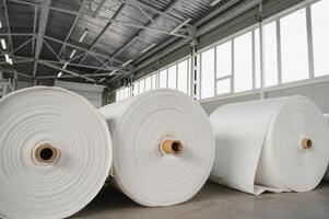 Raw materials warehouse. Many large coils of finished propylene hose made of woven thread for making industrial bags. Polypropylene rolls for packaging. photo