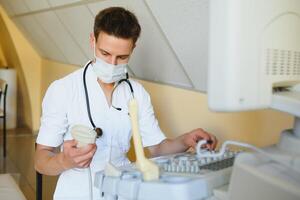 Sonographer operating modern ultrasound machine in clinic photo