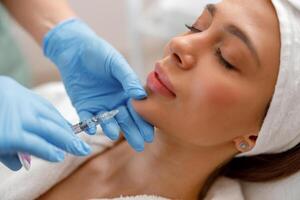 Closeup of young woman receiving hyaluronic acid injection in beauty salon photo