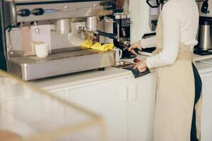 cerca arriba de hembra barista moler café frijol con amoladora máquina mientras trabajando en café foto