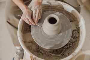 Close up of artisan's hands shaping clay bowl in pottery studio. Pottery art and creativity photo