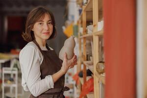 Smiling entrepreneur crafts woman holding mug in pottery studio while looking at camera photo