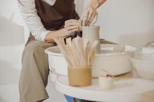 Close up of hands of professional potter molding pot shape on pottery wheel. Ceramics art concept photo