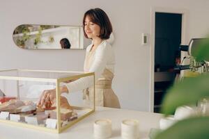 Pretty female waitress hands putting a delicious dessert on a plate standing behind bar counter photo