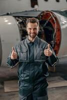 Cheerful airline mechanic showing approval gesture in hangar photo