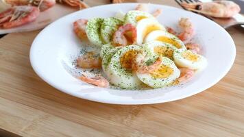 boiled eggs with boiled shrimp in a plate for breakfast, on a wooden board video