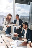 Smiling businessmen drink coffee and discussing documents with graphs and charts photo