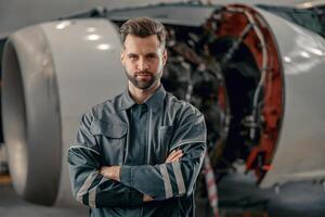 Male airline mechanic standing near airplane in hangar photo