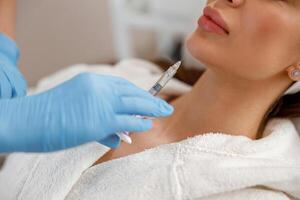 Closeup of young woman getting hyaluronic acid injections in chin at beauty salon photo