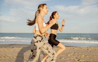 Young athletic women in sportswear is jogging along shore of beach. Concept of healthy living photo