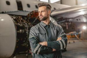 barbado hombre aeronave mantenimiento ingeniero en pie en hangar foto