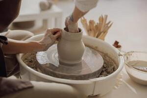 Close up of artisan's hands shaping clay bowl in pottery studio. Pottery art and creativity photo