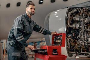 Bearded man airline mechanic working in aircraft hangar photo