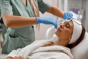 Professional beautician making injections, filling female face with hyaluronic acid photo