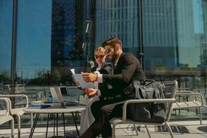 Two business partners working with documents sitting outside of office on cafe terrace photo