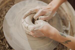 Close up of artisan's hands shaping clay bowl in pottery studio. Pottery art and creativity photo