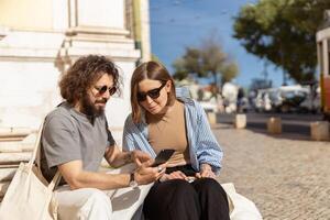 romántico Pareja en amor sentado escalera en antiguo ciudad calle y utilizar teléfono inteligente foto