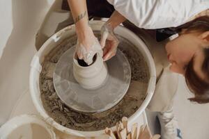 Close up of artisan's hands shaping clay bowl in pottery studio. Pottery art and creativity photo