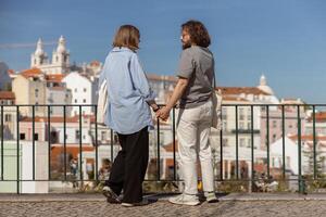 Back view of romantic hipster couple in love holding hands while walking on old city street photo