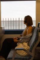 Woman in headphones while traveling in public transport and looking view outside the window photo