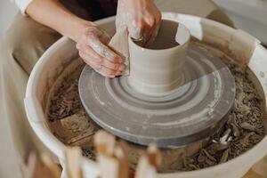 Close up of artisan's hands shaping clay bowl in pottery studio. Pottery art and creativity photo