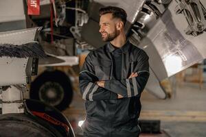 alegre masculino mecánico en pie cerca aeronave en hangar foto