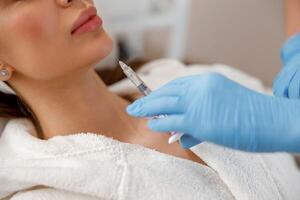 Closeup of young woman getting hyaluronic acid injections in chin at beauty salon photo