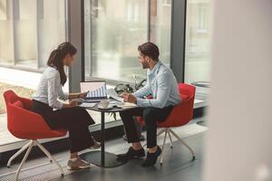 Two diverse business colleagues working together on project sitting in modern meeting room photo