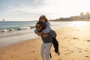 Smiling girlfriend sit on back of boyfriend at sunrise over beach ocean seaside in summer day photo