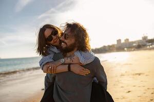 hermoso Pareja en amor abrazando mientras caminando a lo largo el playa en soleado día foto