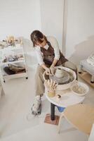 Professional female artisan shaping clay bowl in pottery studio. Ceramics art concept photo