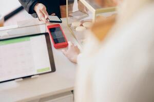 Close up of barista holds out a terminal for contactless paying to a client in coffee shop photo