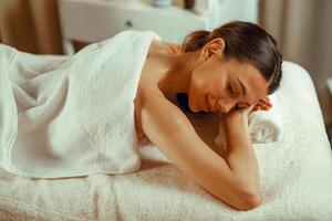 Woman relaxing with eyes closed, enjoying professional massage at spa center photo