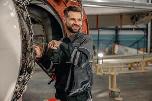 Cheerful male mechanic repairing aircraft in hangar photo