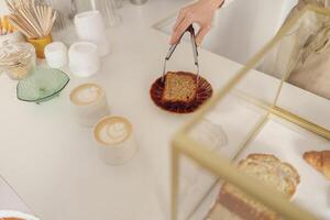 Close-up of female waitress hands putting a delicious dessert on a plate standing behind bar counter photo