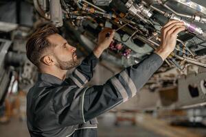 Male maintenance technician repairing airplane in hangar photo